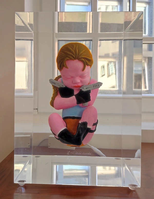 Sculpture d'un fœtus rose avec deux pistolets